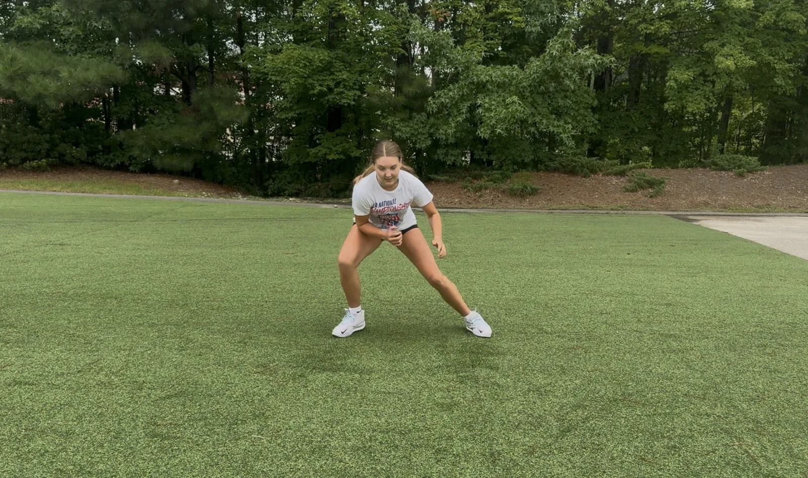 A soccer athlete in a wide athletic stance changing direction on the grass